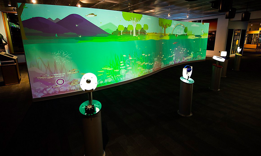 The full exhibit in the museum including the wall and input stations with low lighting