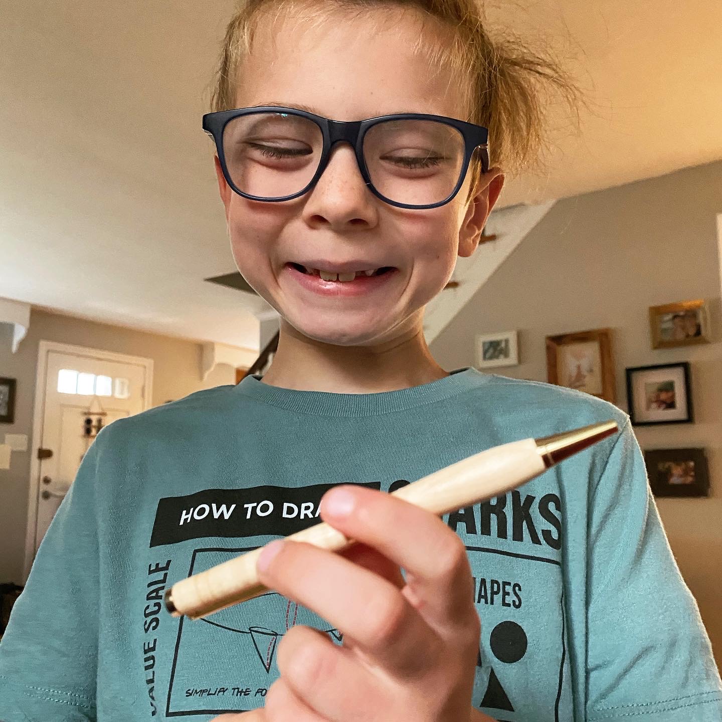 A smiling young boy holding a pen