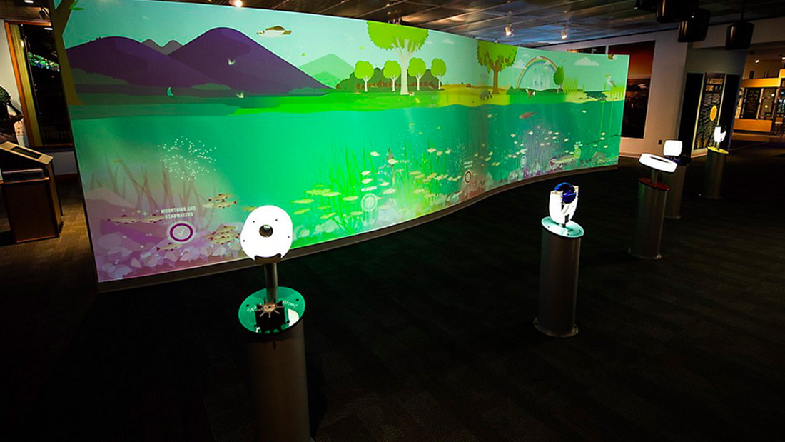 The full exhibit in the museum including the wall and input stations with low lighting